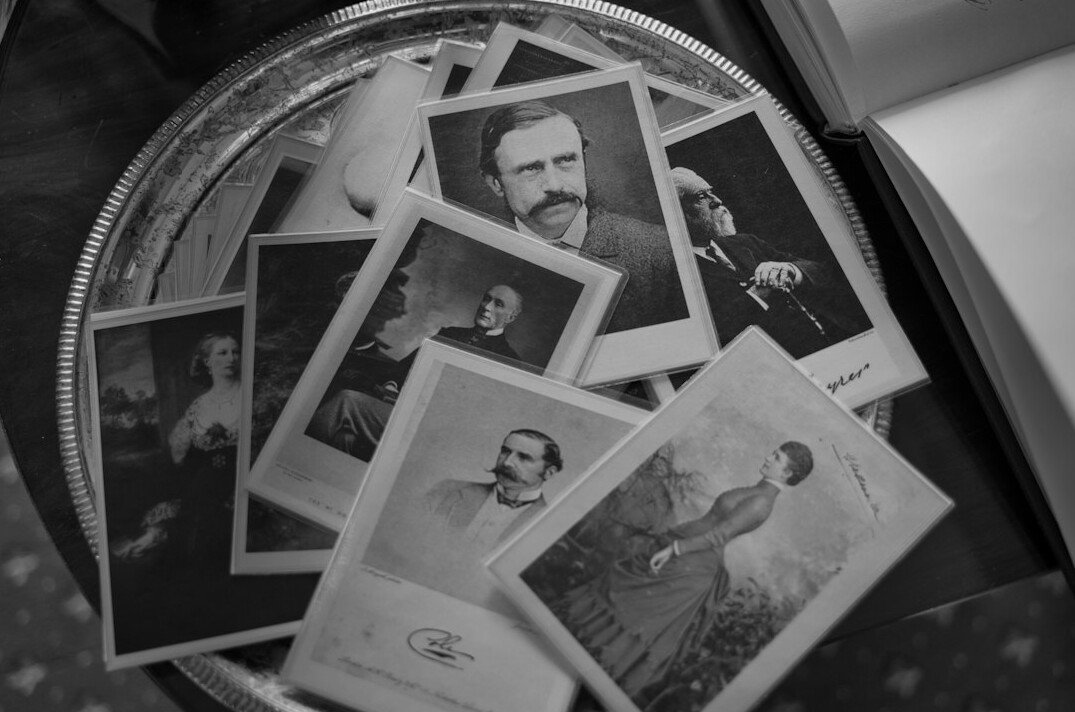 Old black and white photographs spread on a table with a magnifying glass